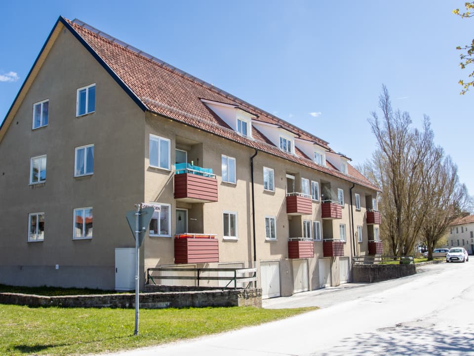 Ljusgult bostadshus med röda balkonger storgatan i Slite. Framför huset är det nedfart till garage och en väg.