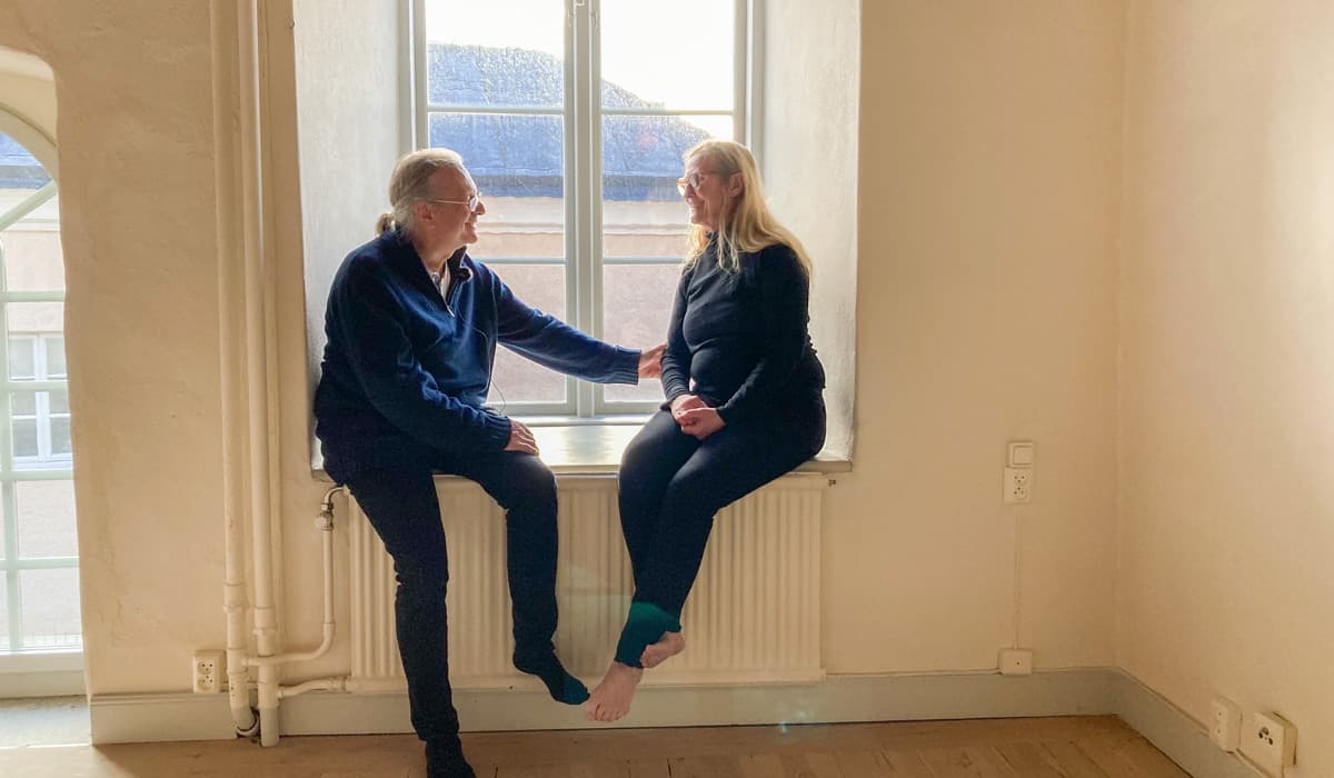 En man och en kvinna sitter tillsammans i ett fönster. Väggarna i rummet är vita.